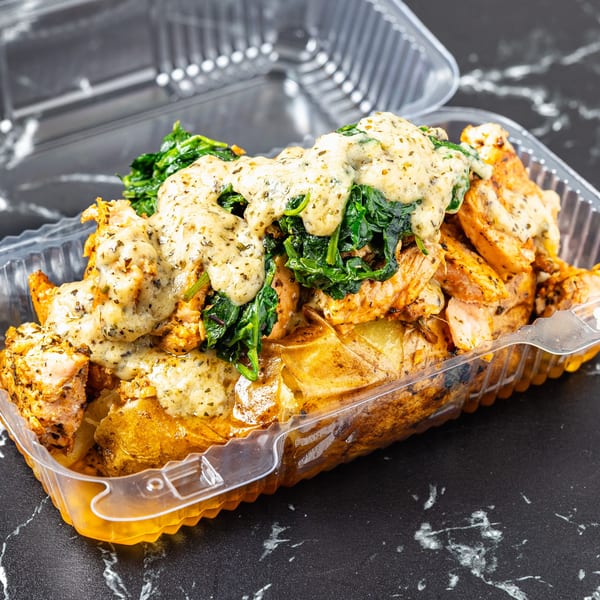 A Watta Potato by Yogis Bistro, an American dish with chicken, spinach, and sauce in a plastic container.